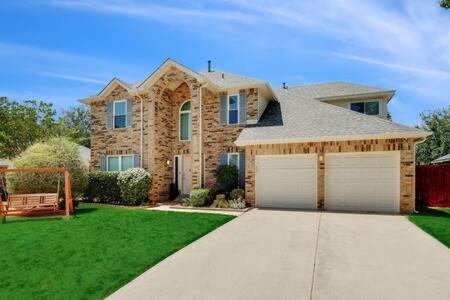 a large brick house with a garage in a yard at Luxury Escape Home with pool spa game room in Flower Mound