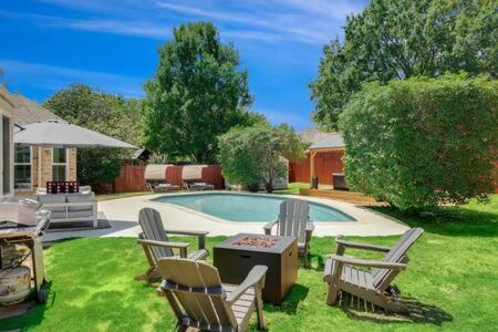 a backyard with a pool with chairs and a table at Luxury Escape Home with pool spa game room in Flower Mound