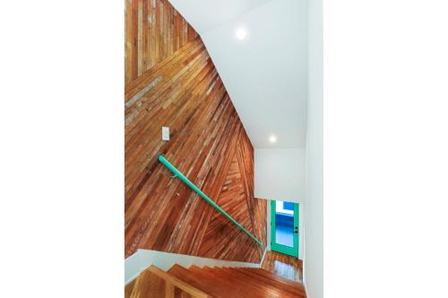 una escalera con paneles de madera y un riel verde en Peace Palace 4803, en Los Ángeles