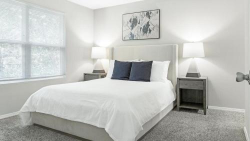 ein weißes Schlafzimmer mit einem weißen Bett und zwei Lampen in der Unterkunft Landing - Modern Apartment with Amazing Amenities (ID9232X12) in Forest Park