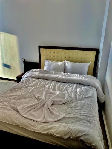 a large bed with white sheets and pillows at Enjoy Giza Pyramids View in Cairo