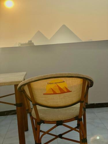 a wooden chair sitting next to a table with mountains on the wall at Enjoy Giza Pyramids View in Cairo