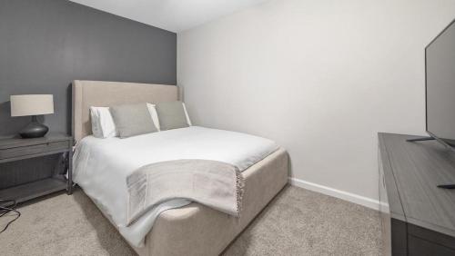 een slaapkamer met een wit bed en een televisie bij Landing - Modern Apartment with Amazing Amenities (ID1292X514) in Lexington