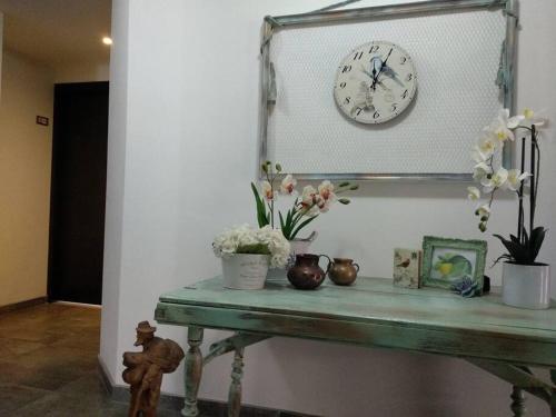 a clock on a mirror above a table with flowers at Perfect Suite, near everything! ¡cerca de todo! in Quito