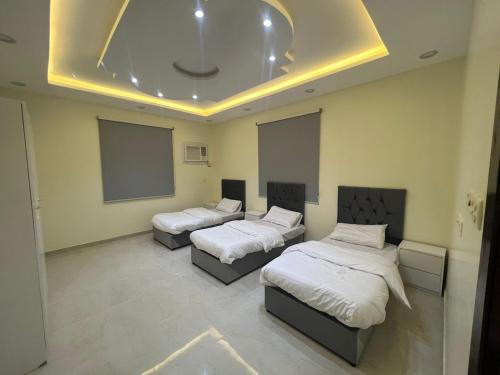um quarto com três camas e um ecrã de projecção em الوسام شقه فندقيه 3 غرف نوم وصاله Al Wissam contains 3 bedrooms and a living room em Taif