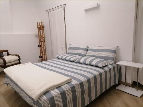 ein Schlafzimmer mit einem Bett mit gestreifter Bettwäsche und einem Stuhl in der Unterkunft MOLO 7 - ANTESITUM - classic, modern and cozy in Malgrate