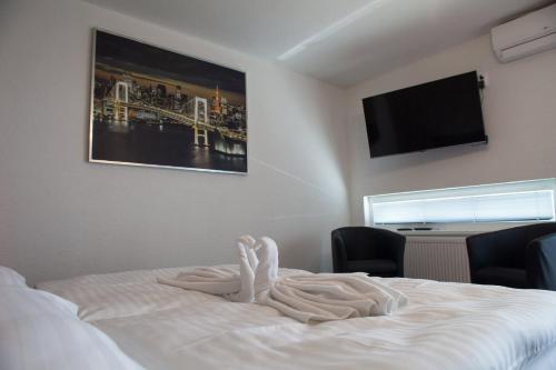 a bed with a towel on it with a flat screen tv at Penzión Arizona in Zlaté Moravce
