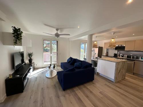un salon avec un canapé bleu et une cuisine dans l'établissement T3 Grand Standing 65m2, vue mer, parking privé et à 200m des plages, à Collioure