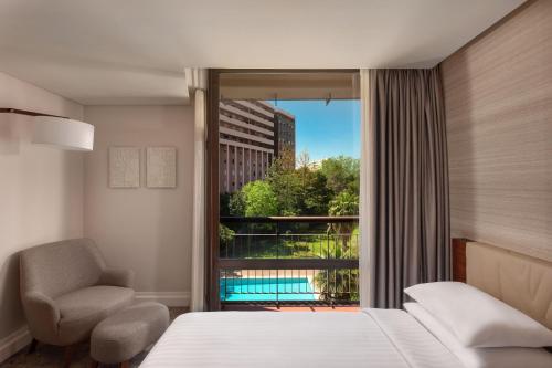 a bedroom with a bed and a chair and a window at Lisbon Marriott Hotel in Lisbon