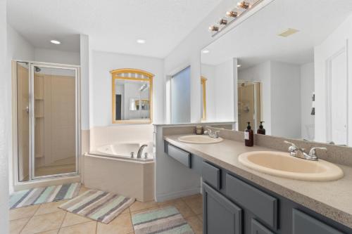 Un baño con dos lavabos, una bañera y una ducha. en South Facing Pool - Family Friendly - Nr Disney, en Kissimmee