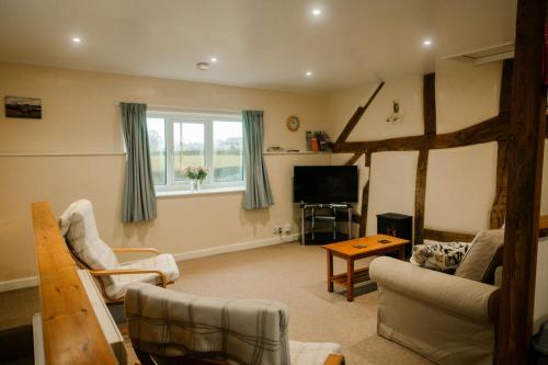 a living room with a couch and a tv at Granary at Tyddyn Isaf in Ruthin