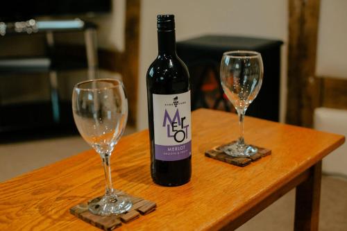 a bottle of wine and two wine glasses on a table at Granary at Tyddyn Isaf in Ruthin