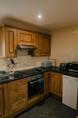 a kitchen with wooden cabinets and a stove top oven at Granary at Tyddyn Isaf in Ruthin
