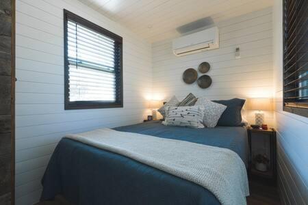 a bedroom with a blue bed and a window at The Blue Ridge "Romantic" Tiny Home Near Magnolia & Baylor in Bellmead