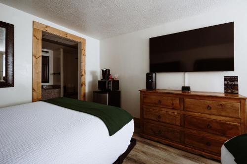 a bedroom with a bed and a dresser with a flat screen tv at Taos Valley Lodge in Taos