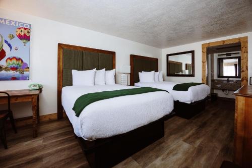 a hotel room with two beds and a desk at Taos Valley Lodge in Taos