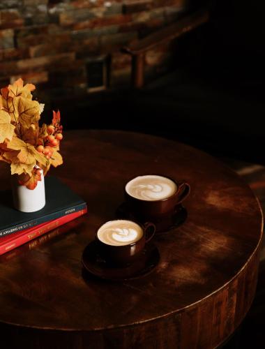 two cups of coffee on a wooden table with a book at Taos Valley Lodge in Taos