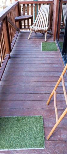 a wooden deck with two benches and green mats at El Regalo El Cuyo in El Cuyo