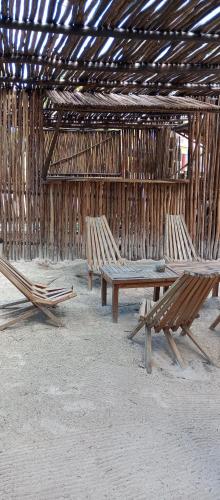 three wooden benches sitting under a straw hut at El Regalo El Cuyo in El Cuyo