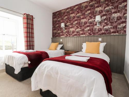 a bedroom with two beds with red and white sheets at The Red Well Country Inn in Carnforth