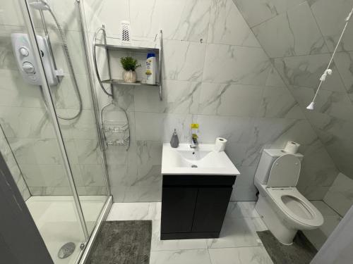 a white bathroom with a shower and a sink and a toilet at Modern apartment next to airport in Marston Green