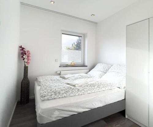 a white bedroom with a bed and a window at Fühle dich wie zu Hause im Taunus in Flörsheim am Main