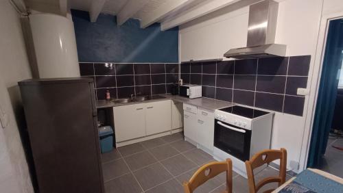 a small kitchen with white appliances and blue tiles at Charmante Maison de Village T3 Rénovée et son Jardin in Revel