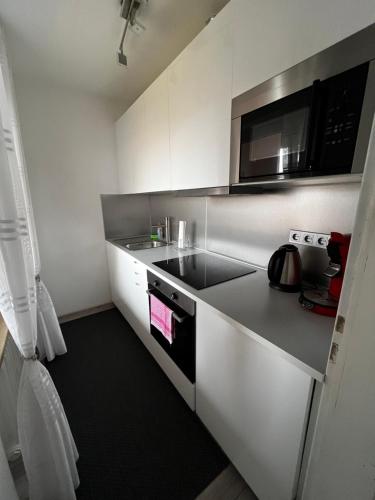 a small white kitchen with a microwave and a stove at Modern Apartment in Augsburg