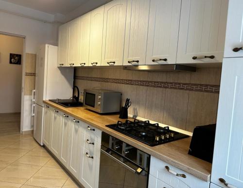 a kitchen with white cabinets and a stove and a microwave at Best Apartment Suceava in Suceava