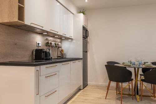 une cuisine avec des armoires blanches et une table avec des chaises dans l'établissement Upscale 3-room apartment 300m from the beaches, à Cannes