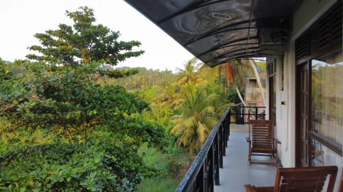a balcony with chairs and a view of the jungle at Mango Shade in Dickwella