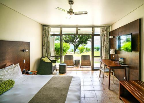 a hotel room with a bed and a desk and chairs at Scenic Matavai Resort Niue in Alofi
