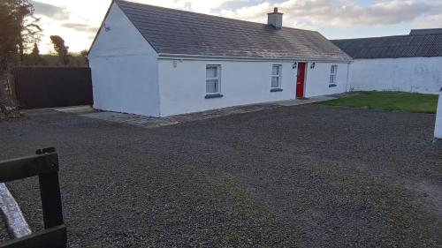a white house with a red door on a gravel driveway at Boola Cottage in Browns Cross Roads