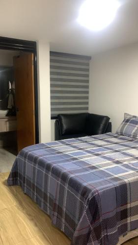 a bedroom with a bed with a blue plaid blanket at San fason 3 in Bogotá