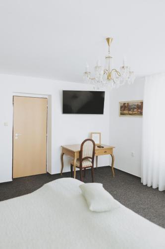 a bedroom with a bed and a table and a chandelier at Penzion Jakub in Lanškroun