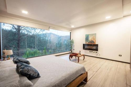 - une chambre avec un grand lit et une grande fenêtre dans l'établissement Sienta el confort en el paraíso, à Cuenca