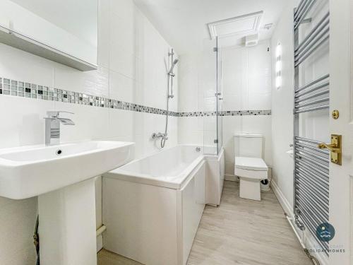 a white bathroom with a sink and a toilet at Bay Retreat - Esplanade sea views parking in Weymouth