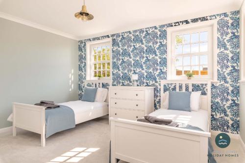 two beds in a room with blue and white wallpaper at Comfort Hill - Luxury hot tub views games room in Overcombe
