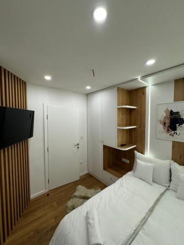 a bedroom with a white bed and a flat screen tv at Mona Luxury Apartments - Free Garage Parking in Sarajevo