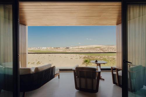 a room with a large window with chairs and a table at Nobu Hotel Los Cabos in Cabo San Lucas