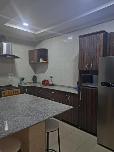 cocina con armarios de madera y encimera de granito en GRACEPOINT APARTMENT en Rubuchi