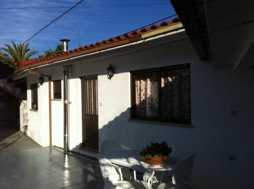 a white house with a table and chairs on a patio at Casa Dos Cabecinhos in Paradamonte