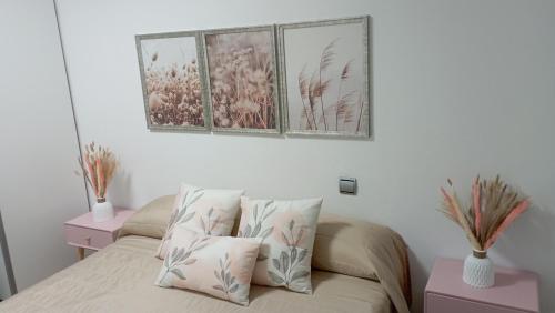 a bedroom with a bed with three pictures on the wall at Clauadris Home ideal para familias in Águilas