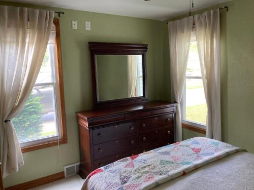 a bedroom with a dresser with a mirror and windows at Cozy Algoma Retreat! Minutes to Beach and Downtown! in Algoma