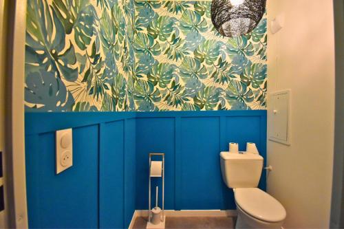 La salle de bains est pourvue de toilettes et d'un mur bleu. dans l'établissement Écho Parisien, à Aubervilliers