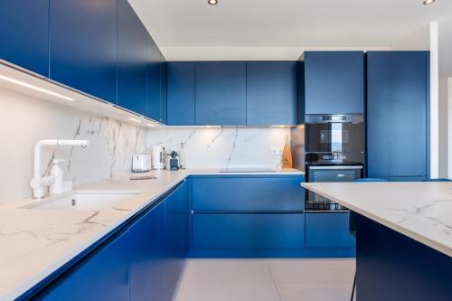 une cuisine bleue avec des comptoirs blancs et des armoires bleues dans l'établissement 3-bedroom apartment sea view terrace and parking, à Cannes