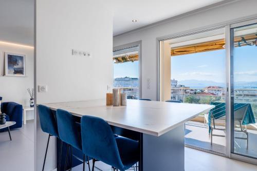 une cuisine avec un grand comptoir blanc et des chaises bleues dans l'établissement 3-bedroom apartment sea view terrace and parking, à Cannes