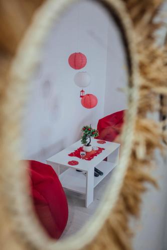 a table with red chairs and a white table with a plant at Nara Apartment in Valjevo