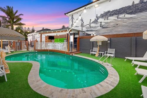 una piscina en un patio con sillas y sombrillas en El Motor Inn, en Port Macquarie