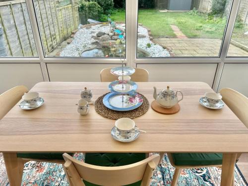 une table en bois avec des tasses et des soucoupes, dans l'établissement Betty's Bungalow, à Lancing